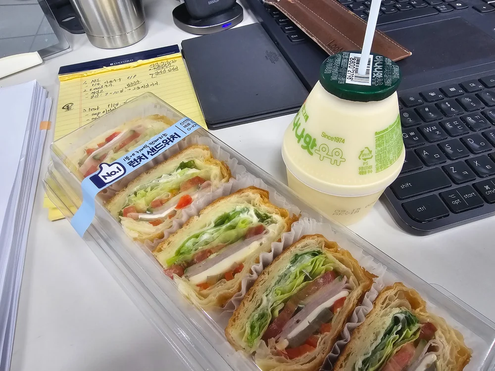 책상 위 샌드위치와 바나나 우유로 준비한 간단한 식사